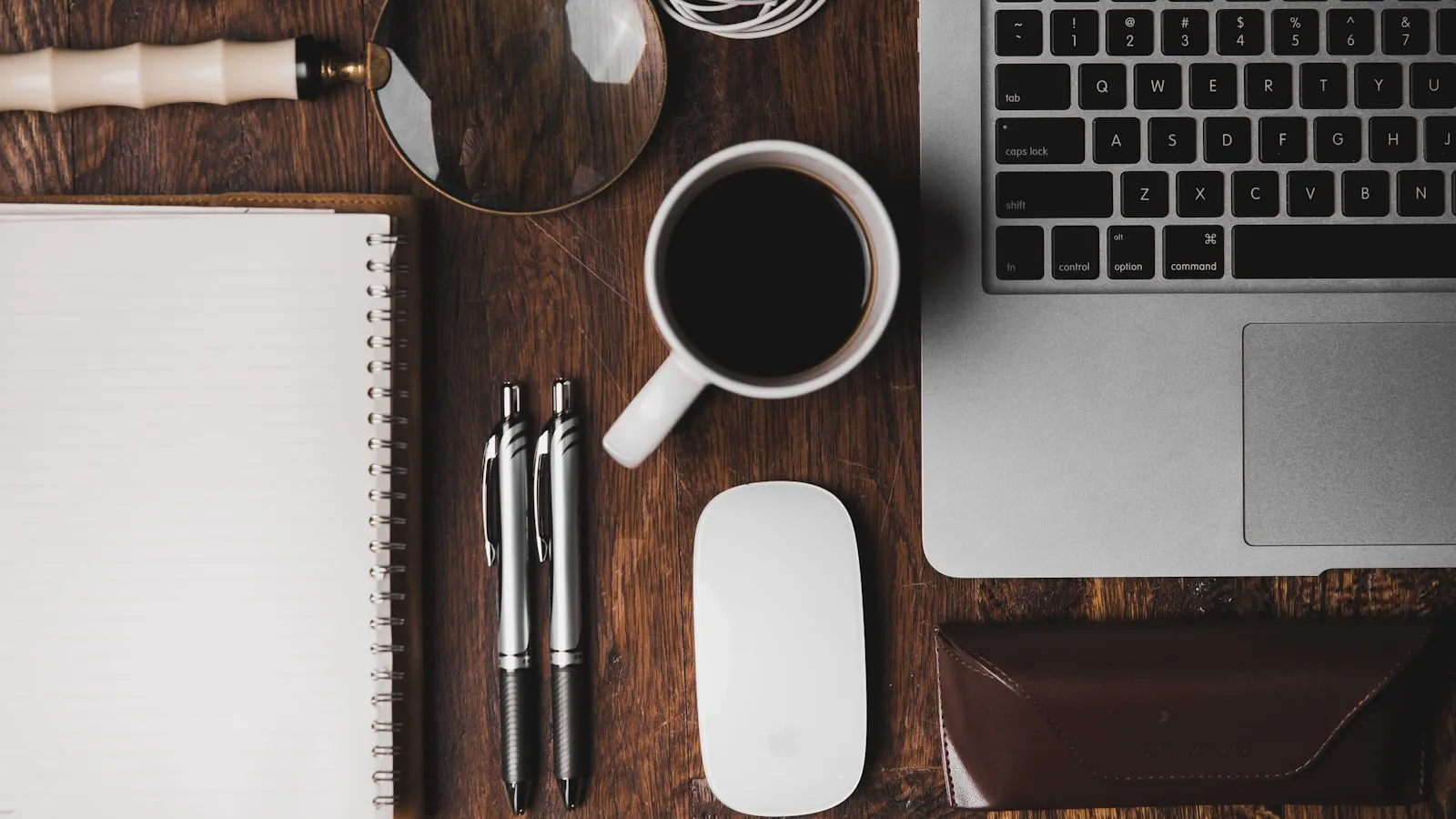 A desk with a notebook, pen, coffee and laptop laid out neatly