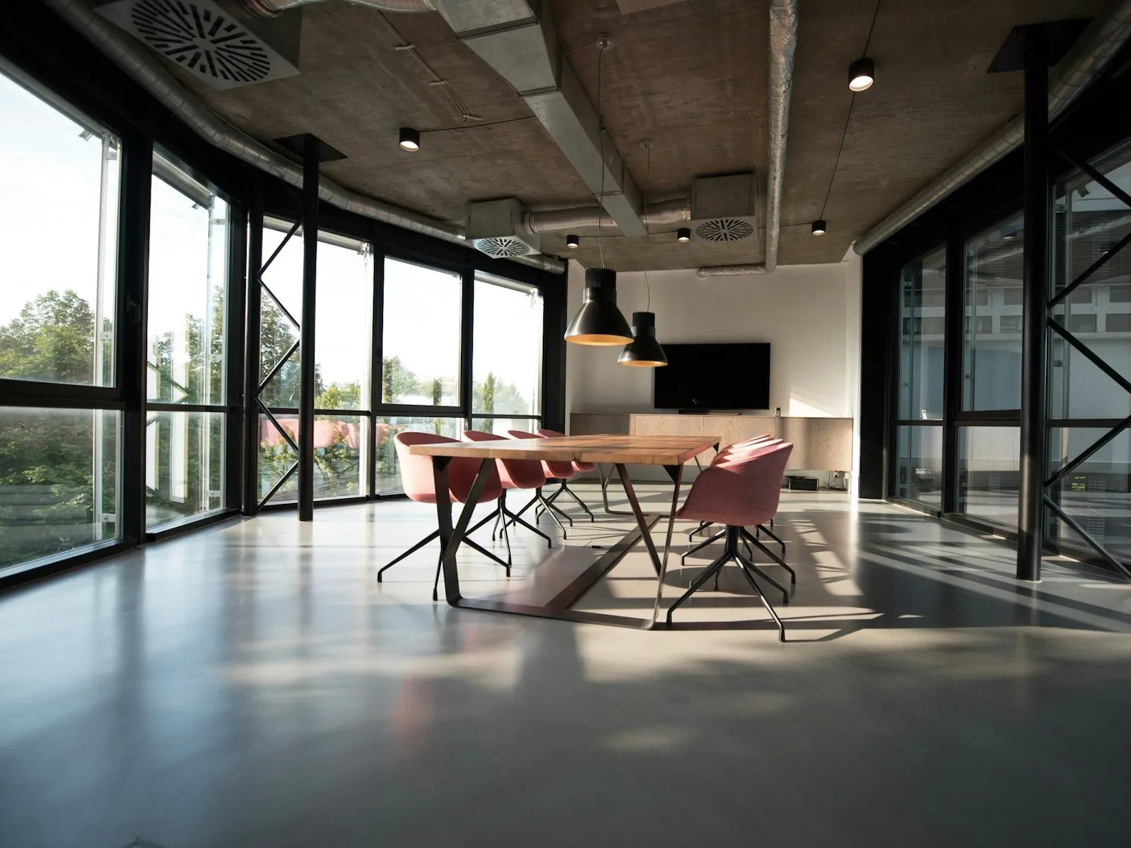 A bright modern office with meeting tables and floor-to-ceiling windows