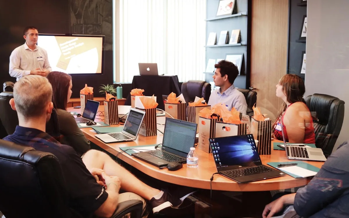 A delivery team working together at a long shared table of laptops.