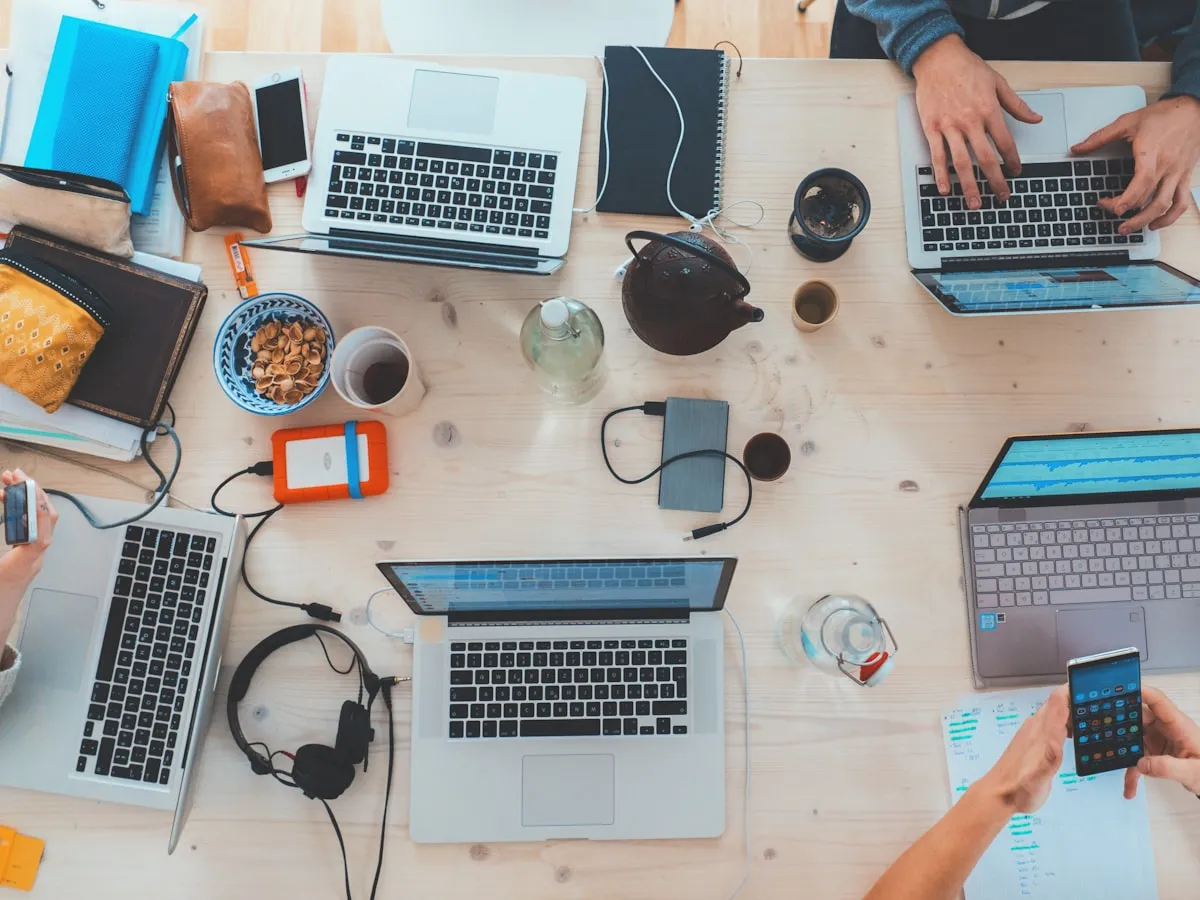 Overhead view of a shared desk covered in laptops and notebooks