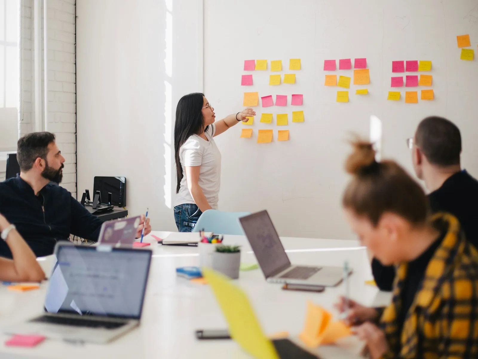 An instructor at a whiteboard covered in sticky notes, leading a small group